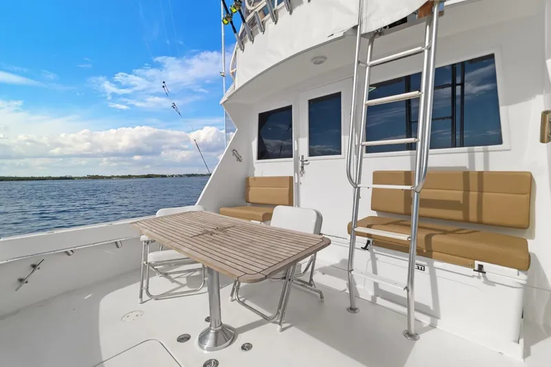 Bella Yacht Photos Pics 1978 Hatteras 45 Convertible yacht deck with seating, table, and ladder, overlooking serene waters.