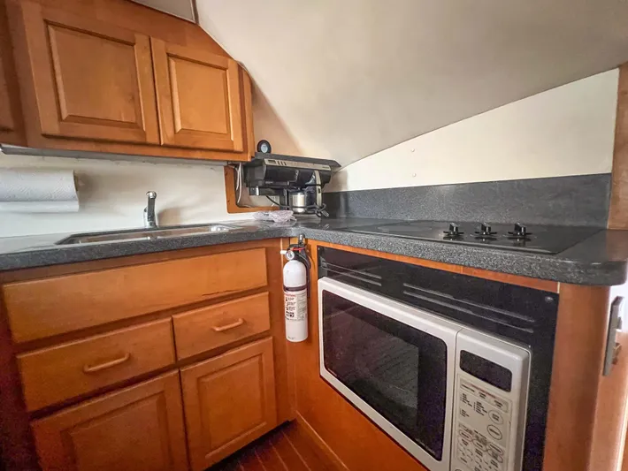 Goggle Eye Yacht Photos Pics 2000 Luhrs 400 Convertible boat kitchen with wooden cabinets, stove, microwave, and sink.