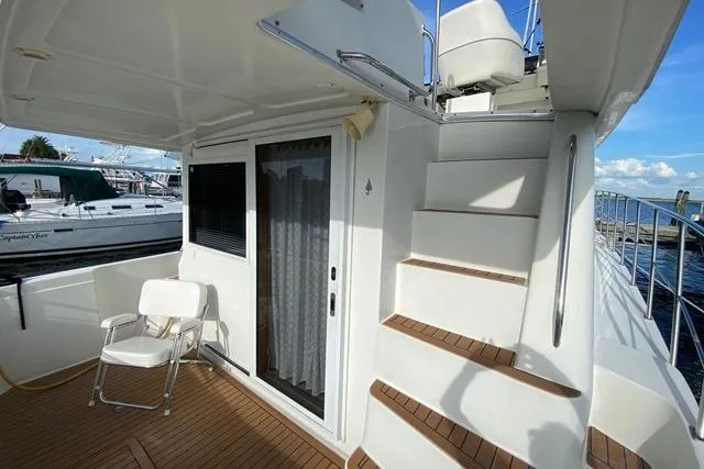 Thistle Do Nicely Yacht Photos Pics 1997 Navigator 4200 yacht deck with stairs, sliding door, and chair by the marina.