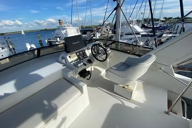 Thistle Do Nicely Yacht Photos Pics Flybridge of 1997 Navigator 4200 yacht with steering wheel and seating, docked at marina.