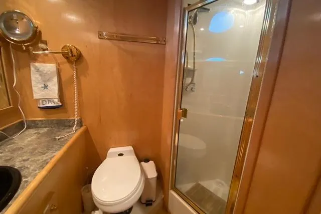 Thistle Do Nicely Yacht Photos Pics 1997 Navigator 4200 yacht bathroom with shower, toilet, and wooden cabinetry.
