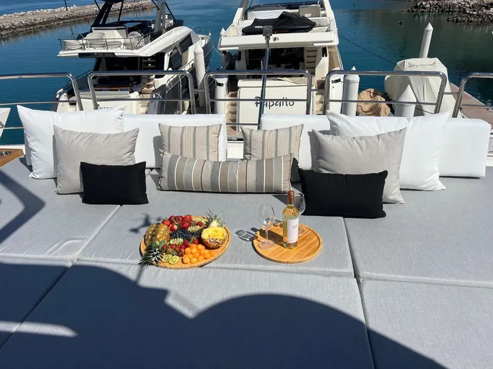 Ganesha Yacht Photos Pics Luxurious Azimut 98 Leonardo yacht deck with cushions, fruit platter, and wine, docked at marina.