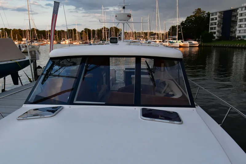 Promesa Yacht Photos Pics 2021 Hylas M44 yacht docked at marina, surrounded by sailboats and waterfront buildings.
