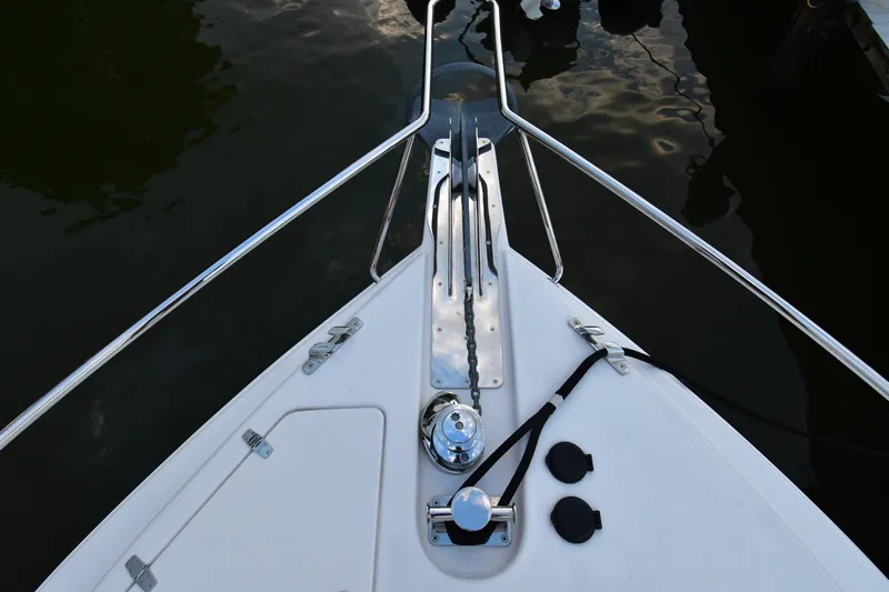 Promesa Yacht Photos Pics Bow of 2021 Hylas M44 yacht with anchor chain and railing, docked on calm water.