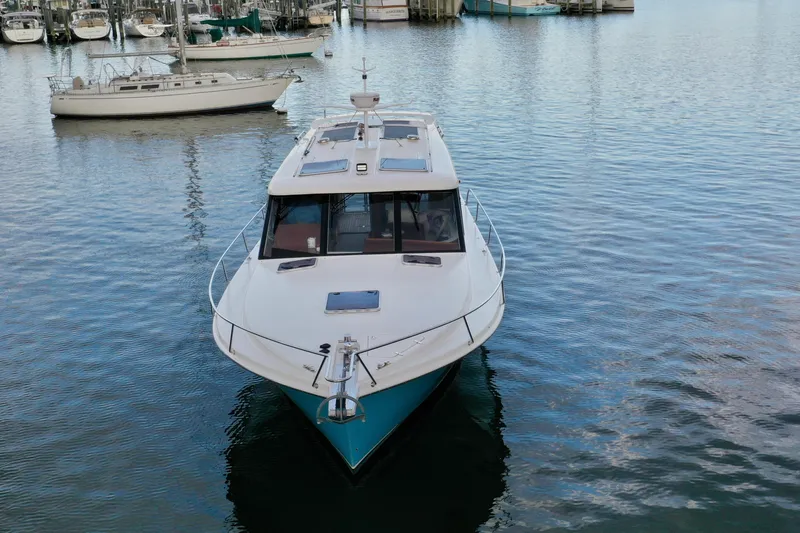Promesa Yacht Photos Pics 2021 Hylas M44 yacht docked in a marina, surrounded by calm water and sailboats.