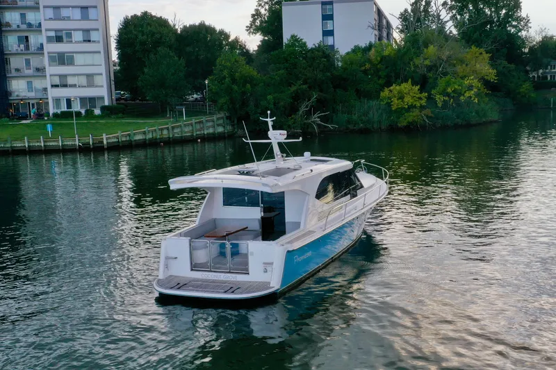 Promesa Yacht Photos Pics 2021 Hylas M44 yacht cruising on a calm river near residential buildings.