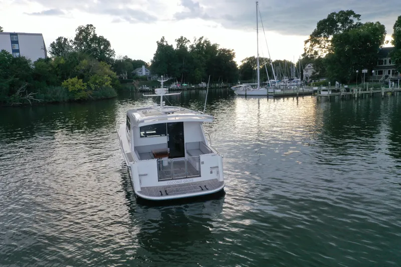 Promesa Yacht Photos Pics 2021 Hylas M44 yacht on calm water near a marina, surrounded by trees.