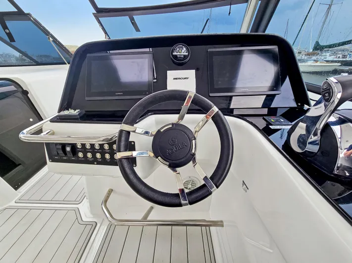 Calypso Yacht Photos Pics Steering wheel and dashboard of 2020 Aquila 36 Sport boat, featuring modern controls and displays.