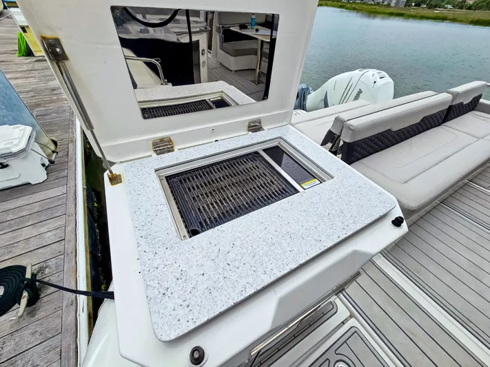 Calypso Yacht Photos Pics Aquila 36 Sport 2020 boat with outdoor grill and seating area by the water.