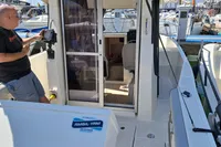 2022 Quicksilver 705 Pilothouse boat with man inspecting equipment at marina.