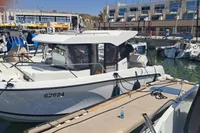 2022 Quicksilver 705 Pilothouse boat docked at a marina with modern buildings in the background.