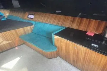 Yacht Photos Pics 2024 Suerte 50 interior with teal seating, wood paneling, and black countertop.