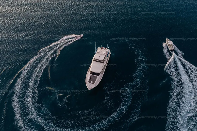 Mijito Yacht Photos Pics Aerial view of Bravo 82 yacht, 2002 model, cruising with two smaller boats in open water.