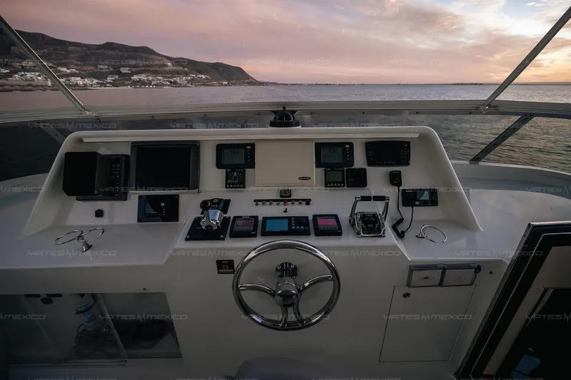 Mijito Yacht Photos Pics Boat cockpit with control panel, steering wheel, and ocean view at sunset. Bravo 82, 2002 model.
