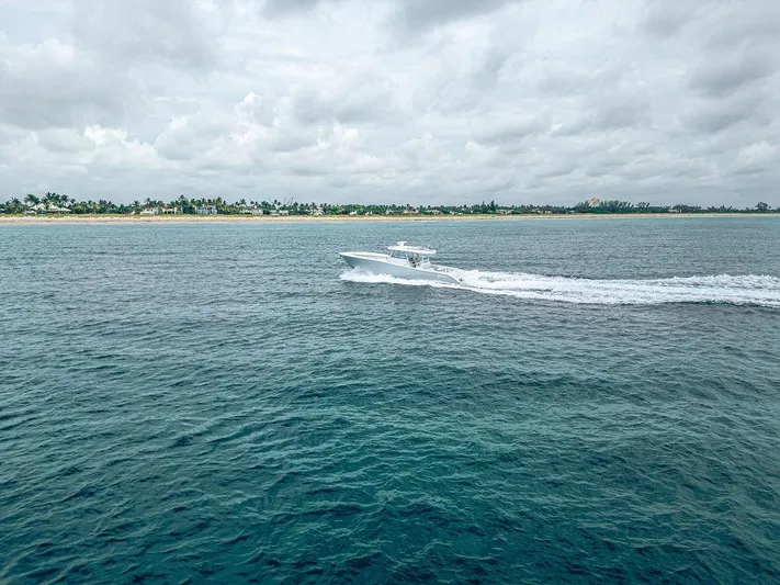  Yacht Photos Pics 2019 Yellowfin 42 boat cruising on open water near a tropical shoreline.