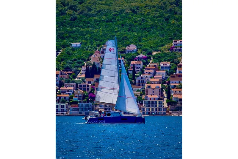 Lucky Dog Yacht Photos Pics Sailing yacht Fountaine Pajot Tanna 47, 2022 model, cruising near coastal village.