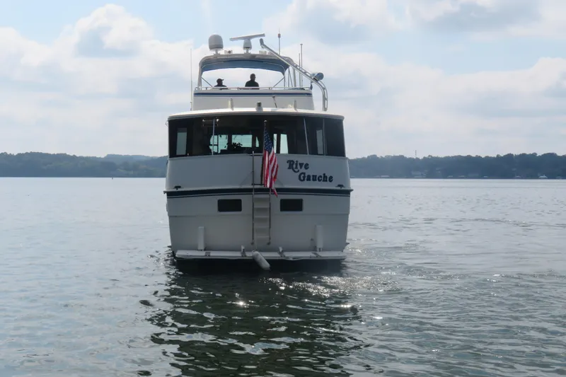 Rive' Gauche Yacht Photos Pics 1986 Hatteras 58 Motor Yacht on calm water, rear view with American flag.