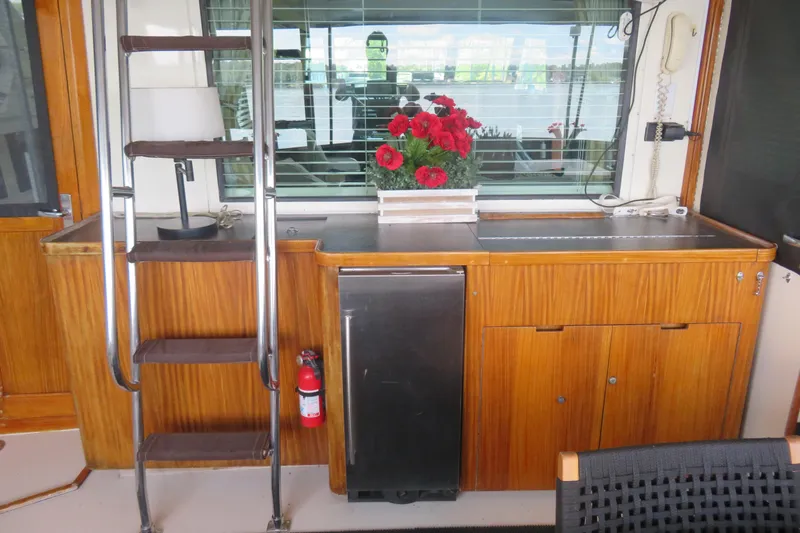 Rive' Gauche Yacht Photos Pics 1986 Hatteras 58 Motor Yacht interior with wooden cabinetry, ladder, and red flowers.