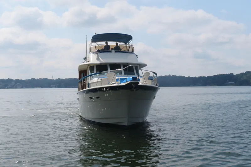 Rive' Gauche Yacht Photos Pics 1986 Hatteras 58 Motor Yacht cruising on a calm lake under a cloudy sky.