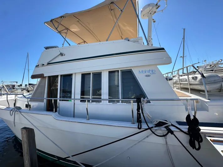 Northstar Yacht Photos Pics 2002 Mainship 430 Trawler docked, featuring a beige canopy and sleek design.