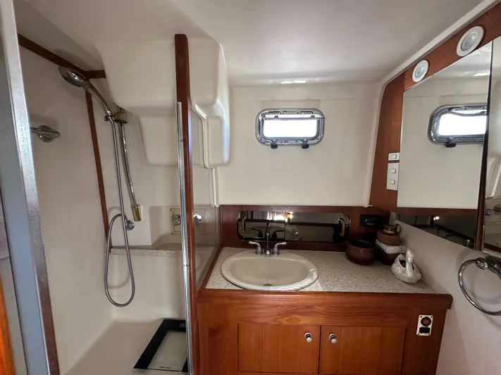 Northstar Yacht Photos Pics 2002 Mainship 430 Trawler bathroom with shower, sink, and wooden cabinetry.