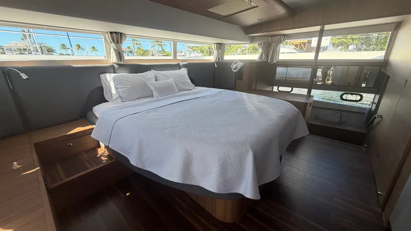  Yacht Photos Pics Luxurious bedroom interior of 2025 Aquila 54 Enclosed Bridge yacht with large windows and elegant decor.