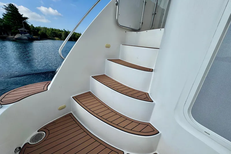 Water Baby Yacht Photos Pics Staircase on 2007 Carver 43 Motor Yacht, overlooking serene water and lush greenery.