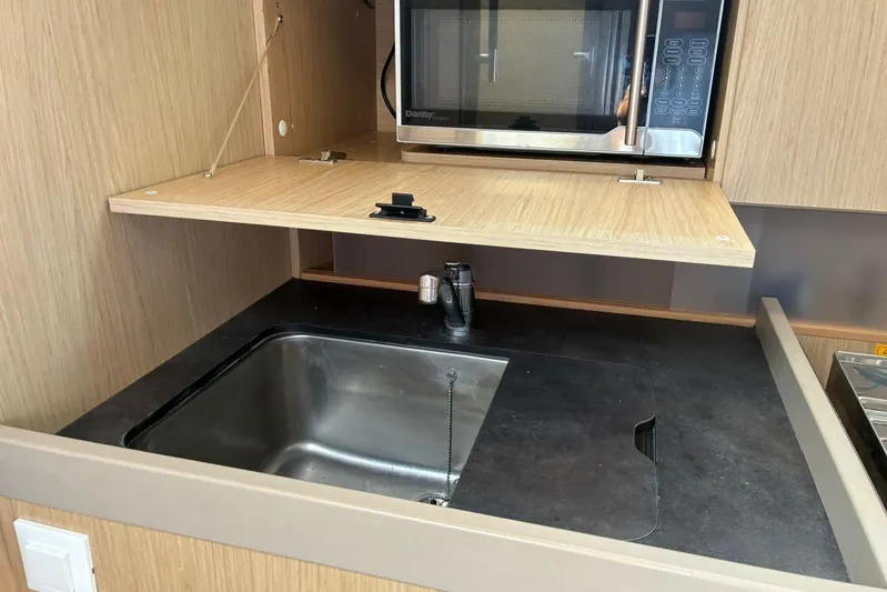  Yacht Photos Pics Modern kitchen area in a 2020 Beneteau Oceanis 41.1 yacht, featuring a sink and microwave.