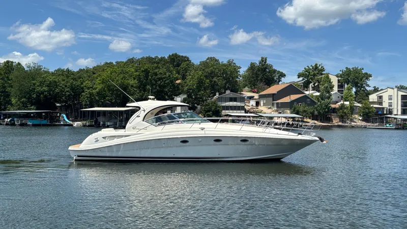  Yacht Photos Pics 2004 Sea Ray 420 Sundancer yacht on a calm lake under a clear sky.