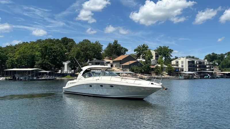  Yacht Photos Pics 2004 Sea Ray 420 Sundancer yacht on a serene lake with houses in the background.