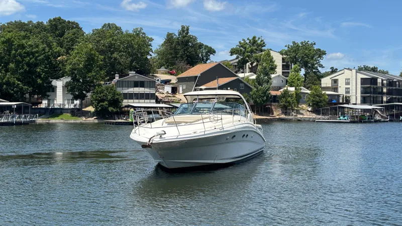  Yacht Photos Pics 2004 Sea Ray 420 Sundancer yacht cruising on a serene lake near waterfront homes.