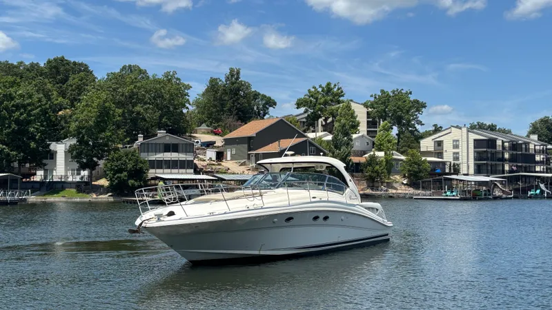  Yacht Photos Pics 2004 Sea Ray 420 Sundancer yacht on a serene lake with houses in the background.