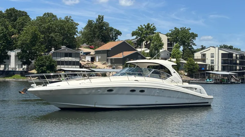  Yacht Photos Pics 2004 Sea Ray 420 Sundancer yacht on a calm lake with houses in the background.