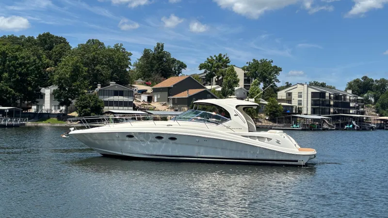  Yacht Photos Pics 2004 Sea Ray 420 Sundancer yacht on a serene lake with houses in the background.
