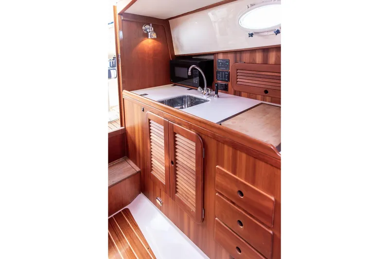 Admiralty Yacht Photos Pics 2005 Hinckley Picnic Boat EP interior with wooden cabinetry and compact kitchen area.