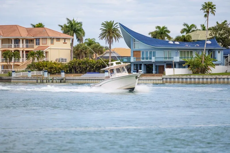  Yacht Photos Pics 2014 Grady-White Canyon 336 boat cruising near waterfront homes with palm trees.