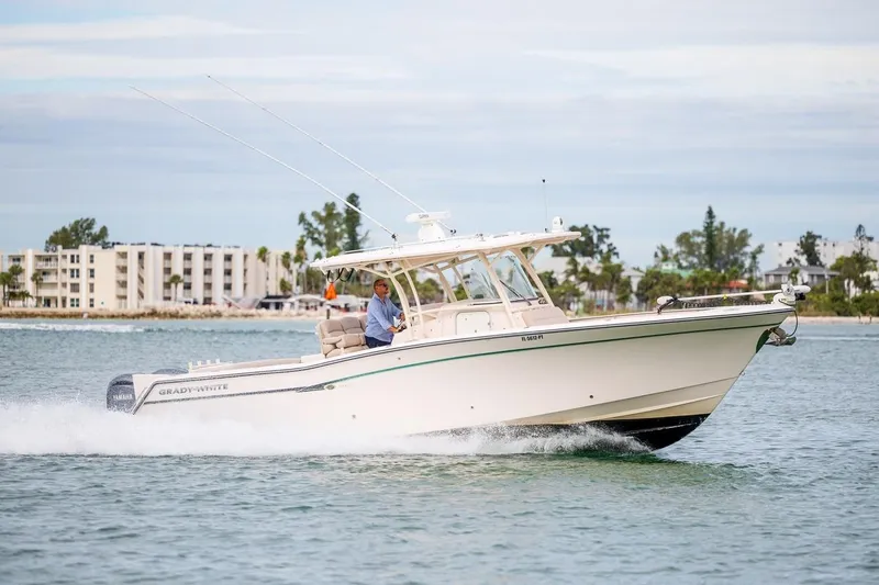  Yacht Photos Pics 2014 Grady-White Canyon 336 boat cruising on water near coastal buildings.