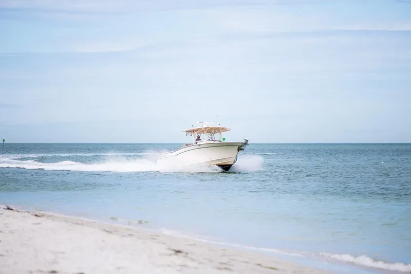  Yacht Photos Pics 2014 Grady-White Canyon 336 boat cruising on open sea near sandy beach.
