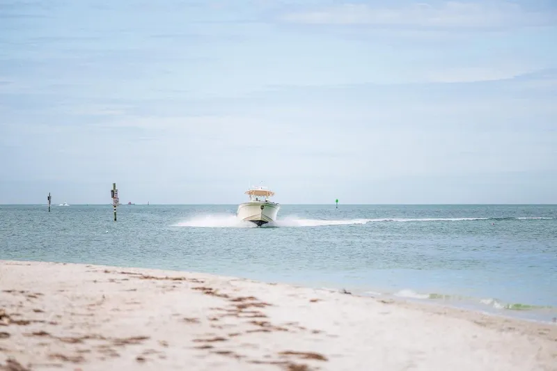  Yacht Photos Pics 2014 Grady-White Canyon 336 boat cruising on open water near sandy beach.