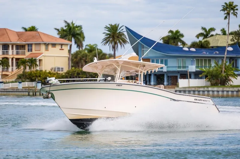  Yacht Photos Pics 2014 Grady-White Canyon 336 boat cruising near waterfront homes, palm trees in background.