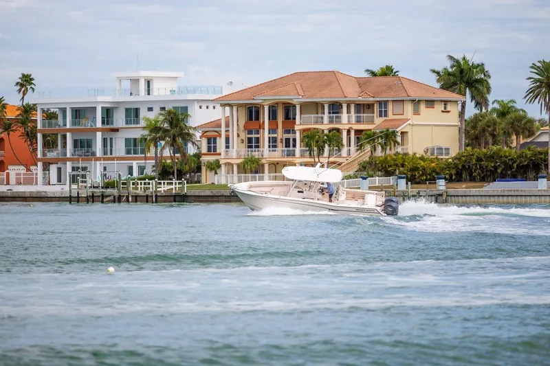  Yacht Photos Pics 2014 Grady-White Canyon 336 boat cruising near waterfront homes and palm trees.