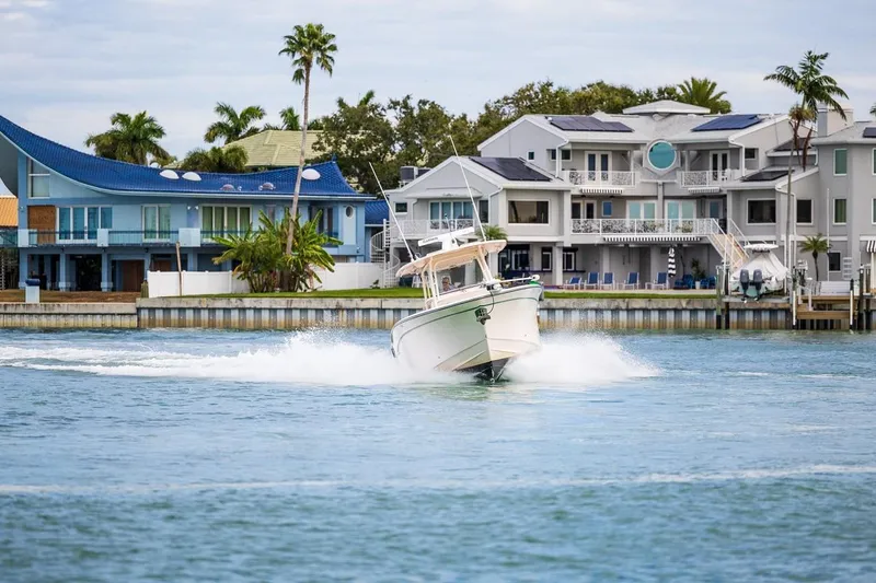  Yacht Photos Pics 2014 Grady-White Canyon 336 boat cruising near waterfront homes with palm trees.