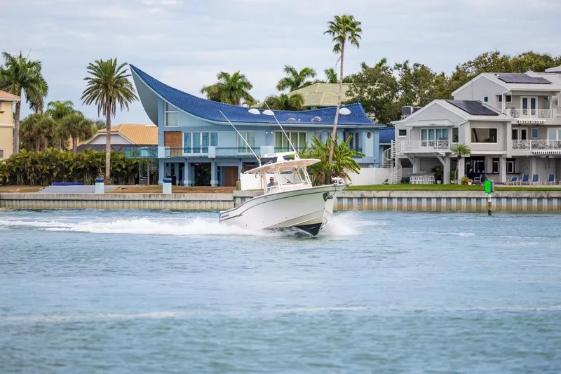  Yacht Photos Pics 2014 Grady-White Canyon 336 boat cruising near waterfront homes and palm trees.