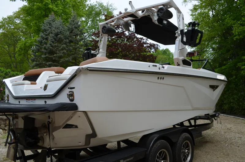  Yacht Photos Pics 2023 Nautique Super Air Nautique S23 boat on trailer, surrounded by trees.