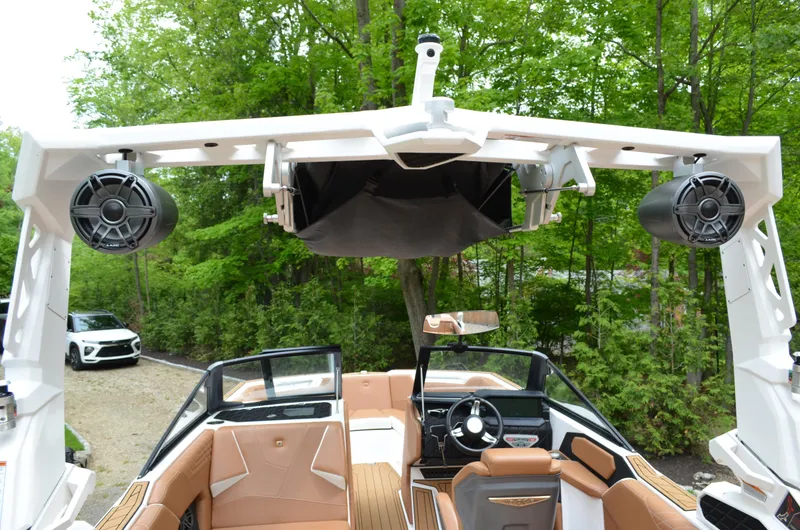  Yacht Photos Pics 2023 Nautique Super Air Nautique S23 interior with speakers and seating, surrounded by lush greenery.