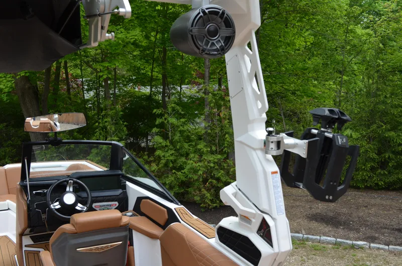  Yacht Photos Pics 2023 Nautique Super Air Nautique S23 interior with speakers and seating, surrounded by lush greenery.