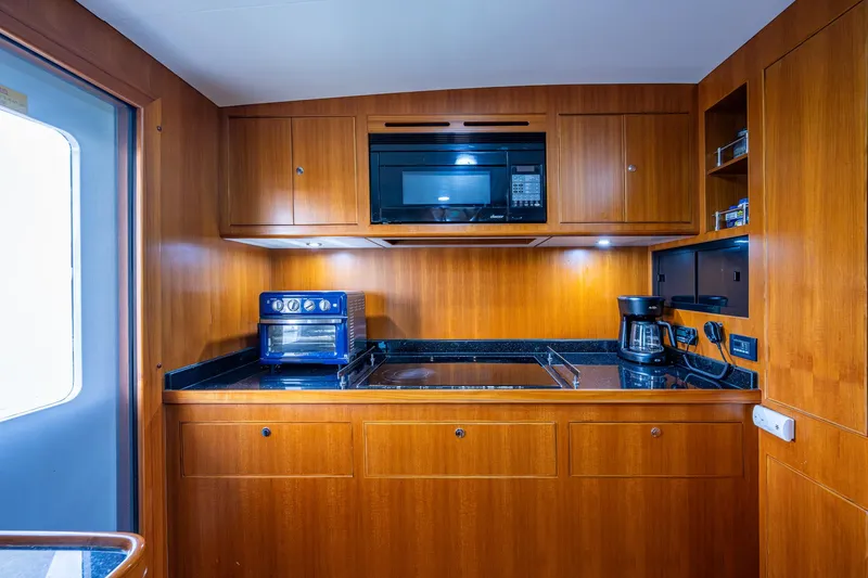 Pivot Yacht Photos Pics 2013 Marlow Explorer Enclosed Bridge (CB) yacht kitchen with wooden cabinetry, microwave, and appliances.