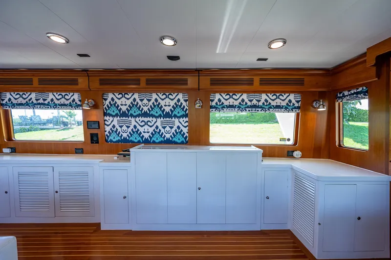 Pivot Yacht Photos Pics Interior of 2013 Marlow Explorer Enclosed Bridge (CB) with wooden cabinetry and patterned curtains.