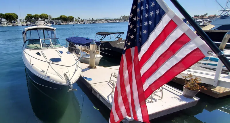 Just Becuz Yacht Photos Pics 2007 Sea Ray 310 Sundancer docked near American flag, sunny marina setting.