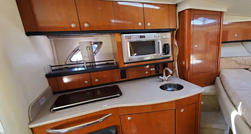 Just Becuz Yacht Photos Pics 2007 Sea Ray 310 Sundancer interior kitchen with wood cabinetry, microwave, and sink.